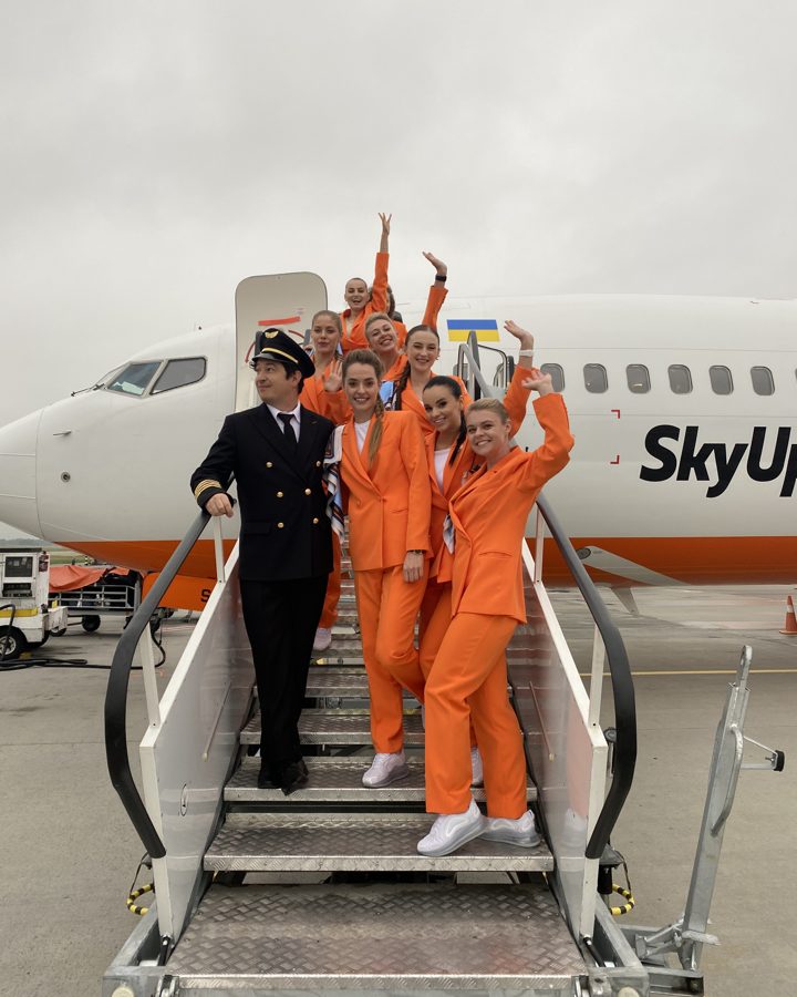 SkyUp crew in the new orange uniform and white sneakers on the airstair